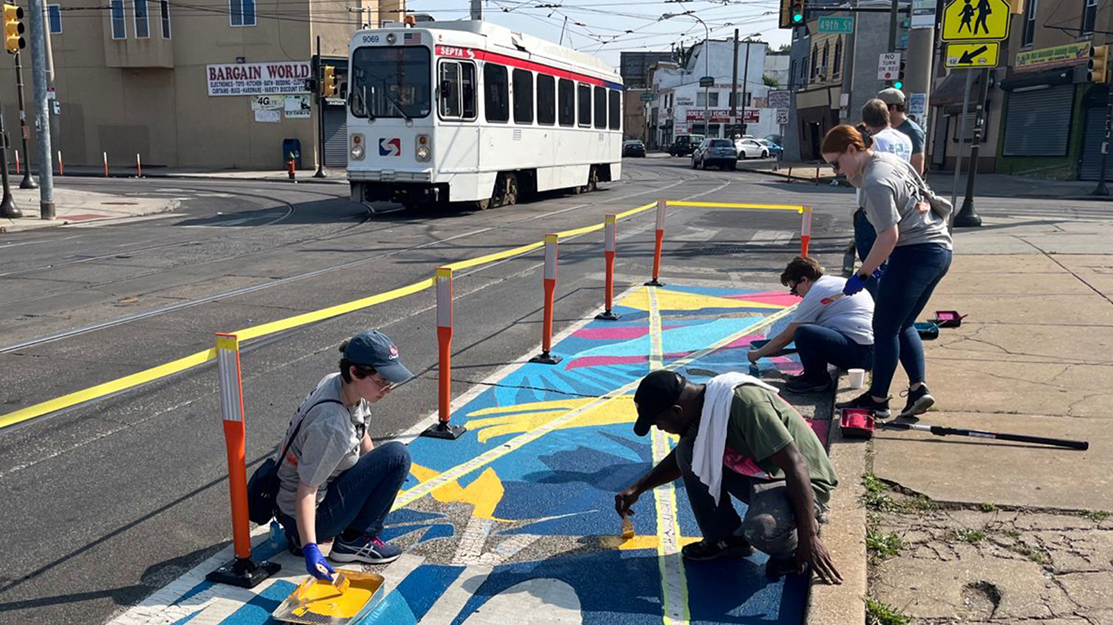 People painting colorful street markings for a bus stop in Philadelphia, PA.